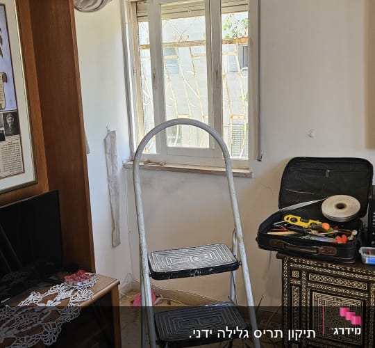 סולם וכלי עבודה ליד חלון עם תריסים